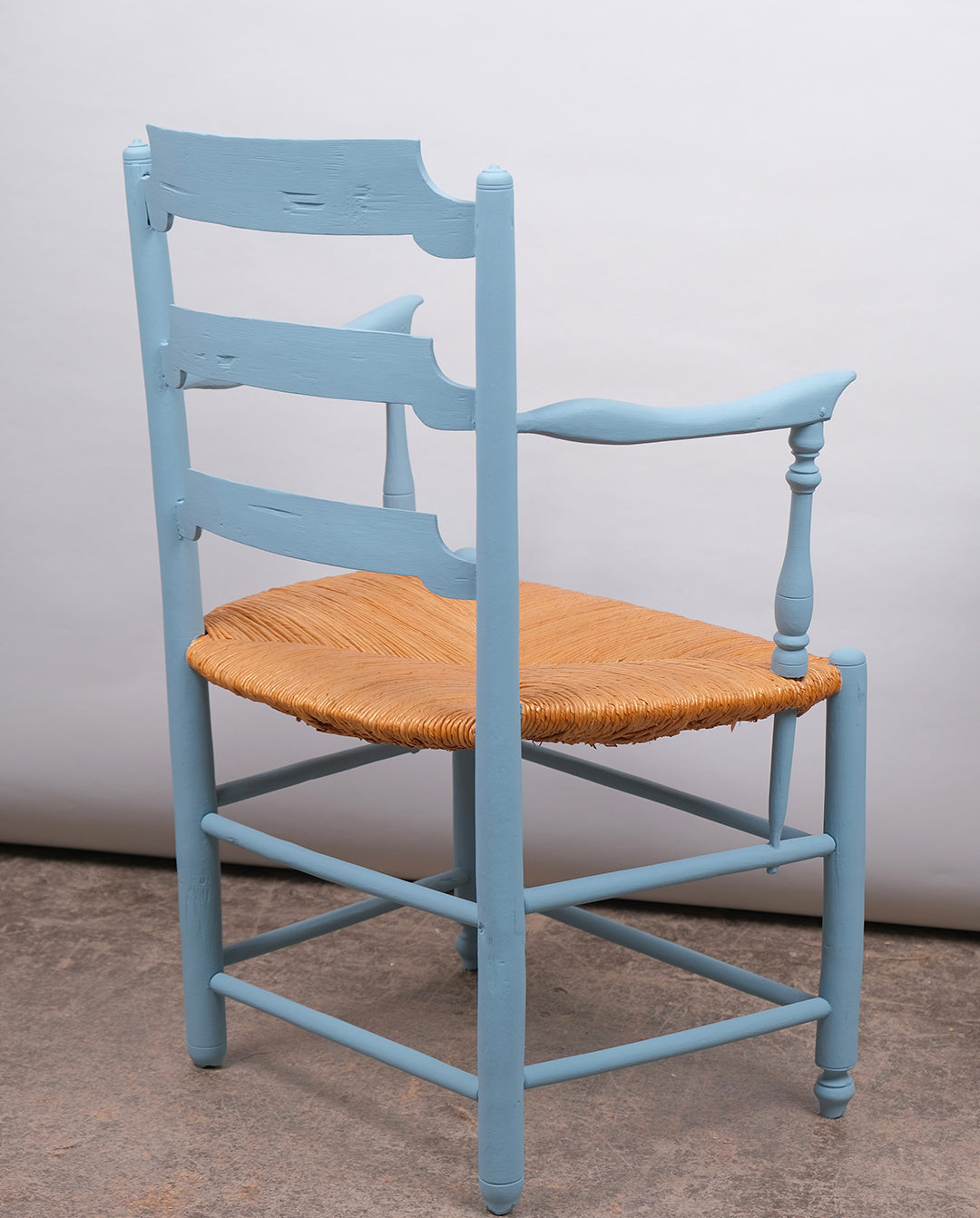 Fauteuil en bois repeint à l'atelier en bleu clair et assise paillée.