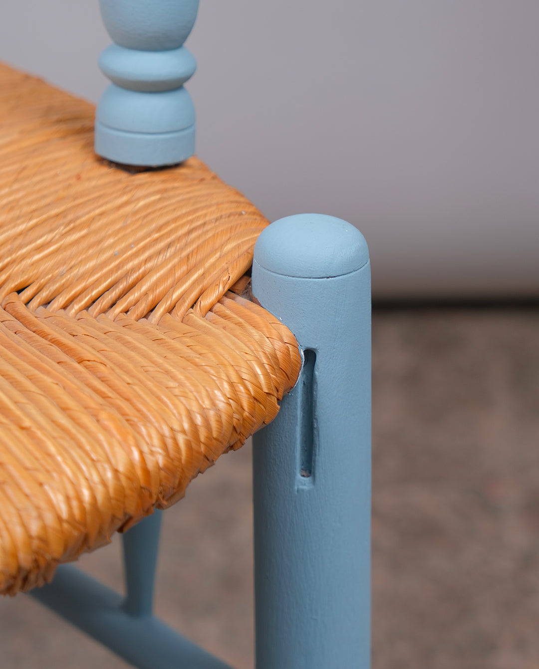 Fauteuil en bois repeint à l'atelier en bleu clair et assise paillée.