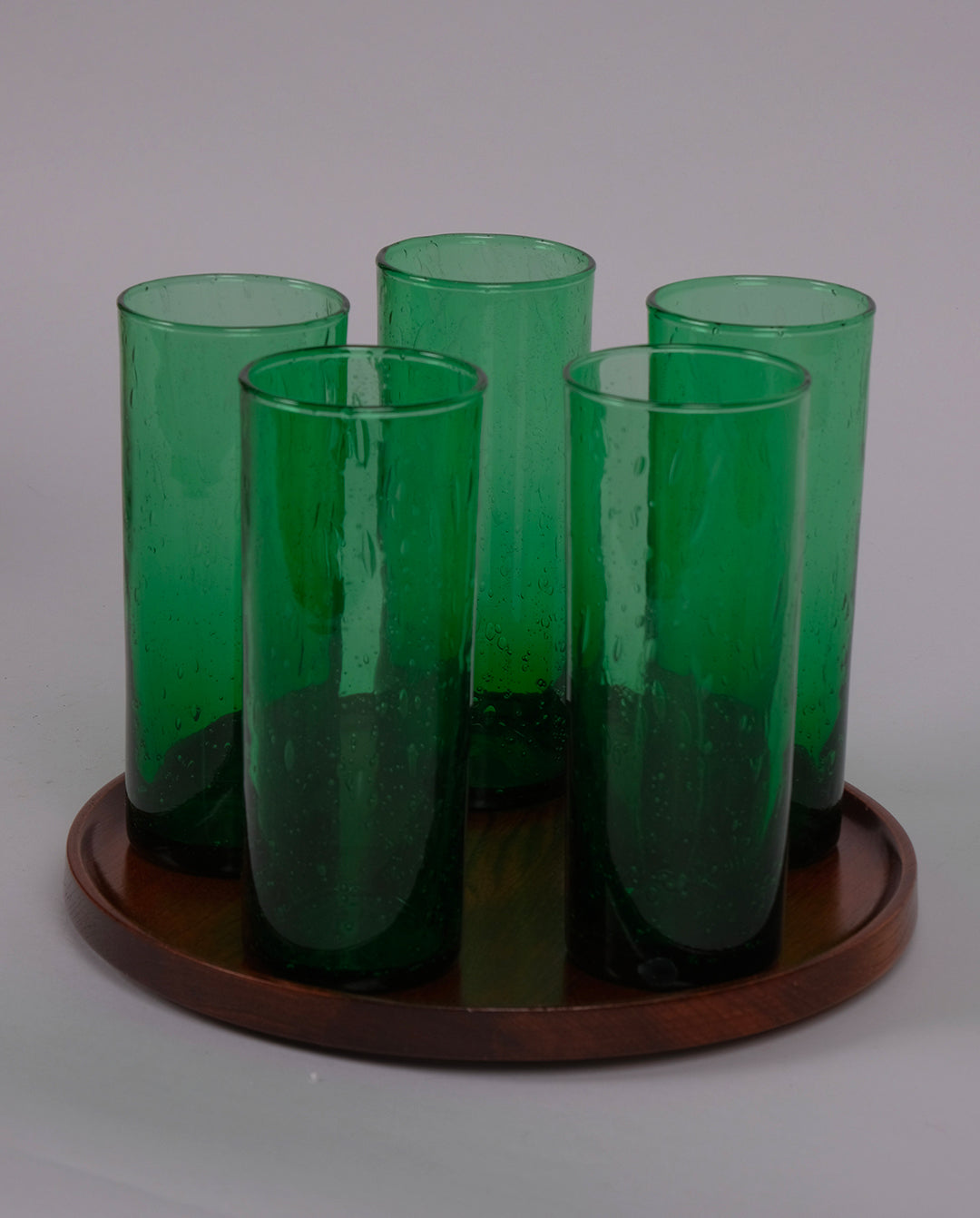 Verres hauts en verre bullé teinté vert sur un plateau en pin